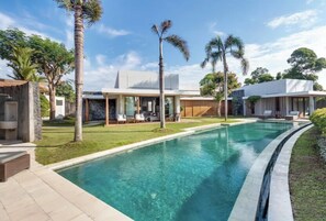 A modern pool area with a clear pool, surrounded by palm trees and a well-maintained lawn. - VILLA MILA CANGGU (Canggu)