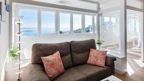 A modern living room with a large window, a sofa with decorative pillows, a floor lamp, and a view of the sea. - Magic of the ocean, Front Line Beach Apartment (TORREMOLINOS)