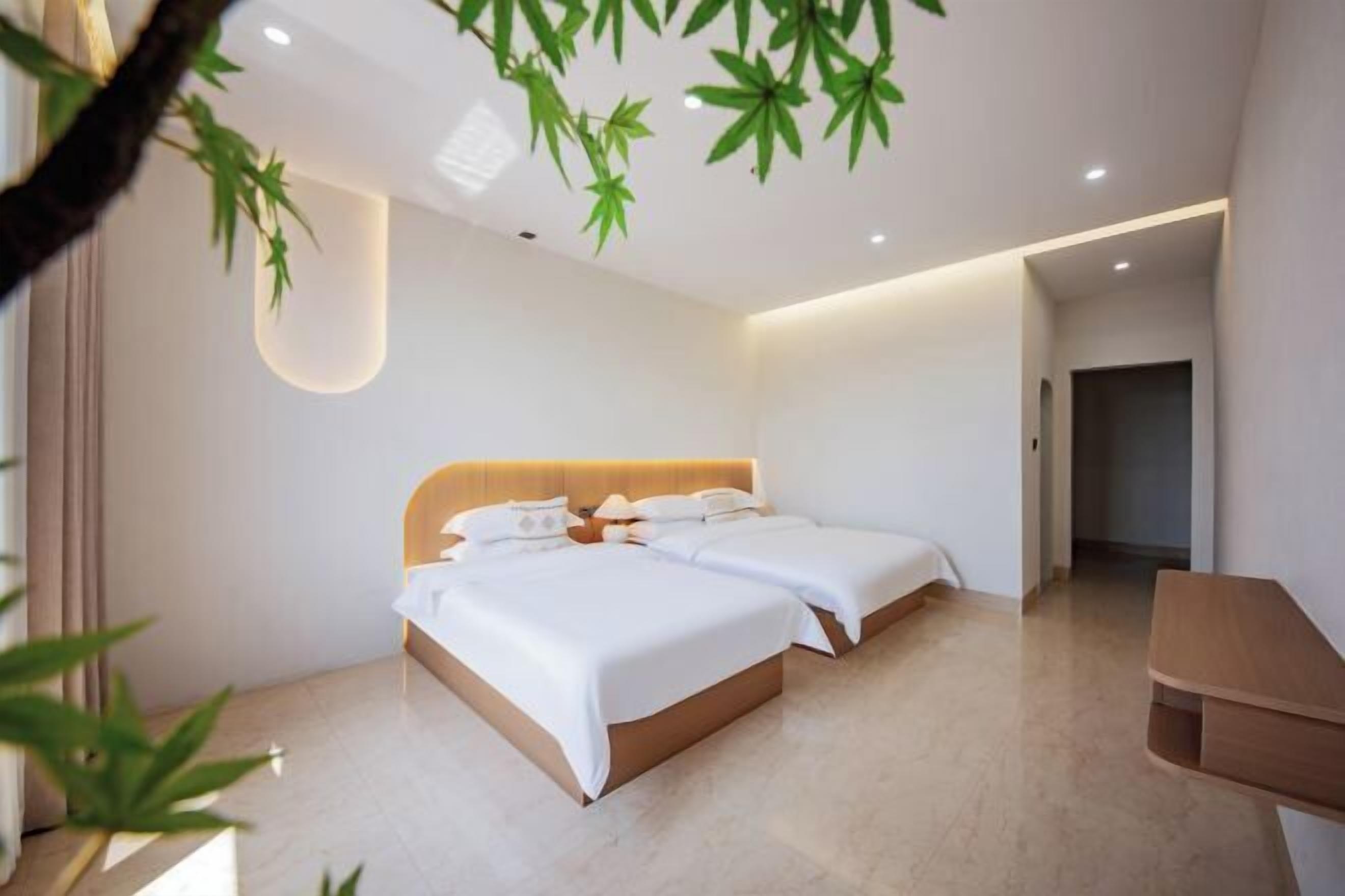Une chambre d’hôtel moderne avec un grand lit, une table de chevet en bois et un plafond orné de plantes suspendues.