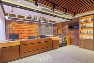 Zona de recepción con un mostrador de madera, una estación de café y una estantería.