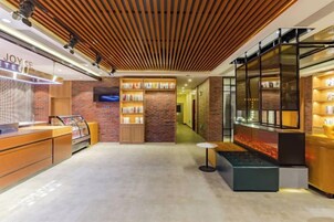 A modern hotel lobby with a reception desk, a seating area, and a display of products.