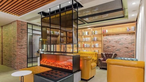 A modern lounge area with a fireplace, leather sofas, and bookshelves. - Shexian Huizhou Gucheng store JAMES JOYCE COFFETEL (She County)