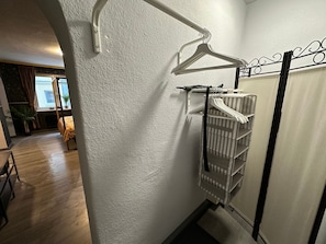 Una habitación con pared blanca, un radiador y un perchero blanco con estantes.