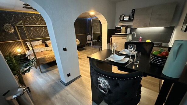 A modern kitchen with a dining area, featuring a black chair with a decorative design, a microwave, and a coffee machine.