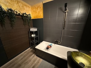 Un baño moderno con bañera, ducha y un lavabo verde.