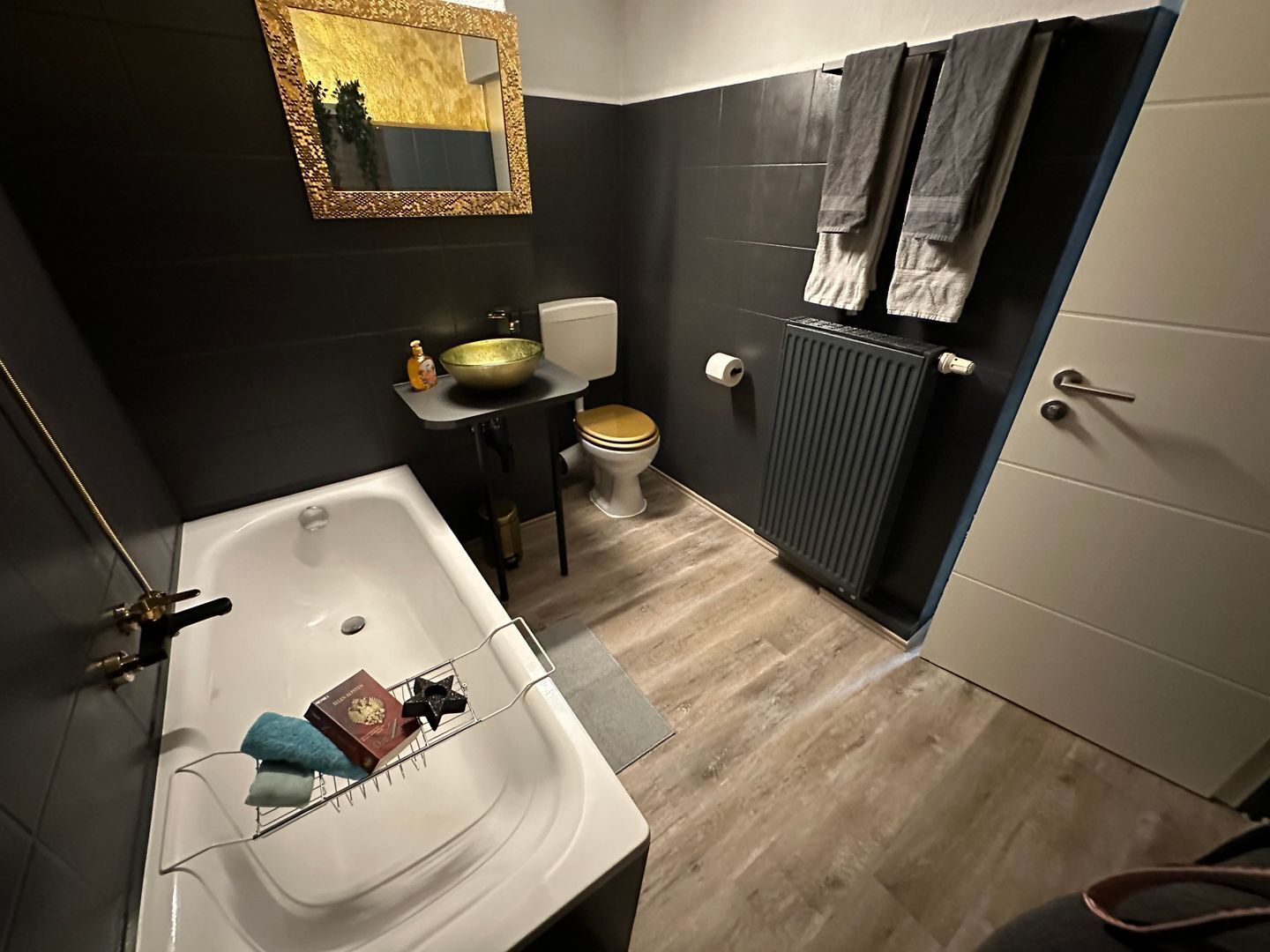 Un baño moderno con bañera, lavabo, inodoro y radiador.