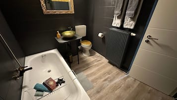A modern bathroom with a bathtub, sink, toilet, and a radiator.