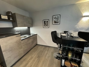 Una cucina moderna con piano cottura integrato, lavello e zona bar con sgabelli e portabottiglie.