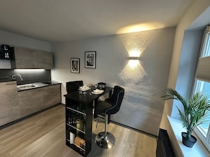 Una cocina moderna con comedor, un taburete negro y una planta en maceta cerca de la ventana.