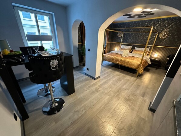A modern bedroom with a bed, a desk, and a chair. There is a window and a door.