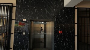 An elevator entrance with a black marble wall and a metal gate. - Sri Srinivasa Residency (Puducherry)