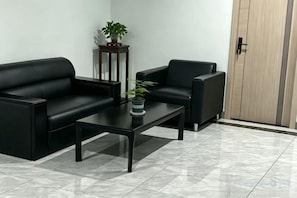 A room with two black sofas, a small table, a potted plant, and a wooden wardrobe. - 99inn Selected Preferred Hotel (Shanghai Fengjing Ancient Town) (Shanghai)