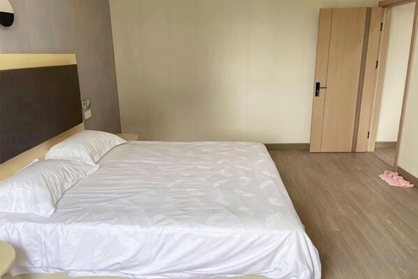 Une chambre à coucher avec un lit, une armoire en bois et une porte.