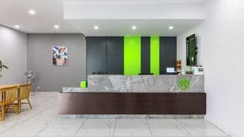 A reception area with a marble counter, a green and black color scheme, and a seating area with chairs.