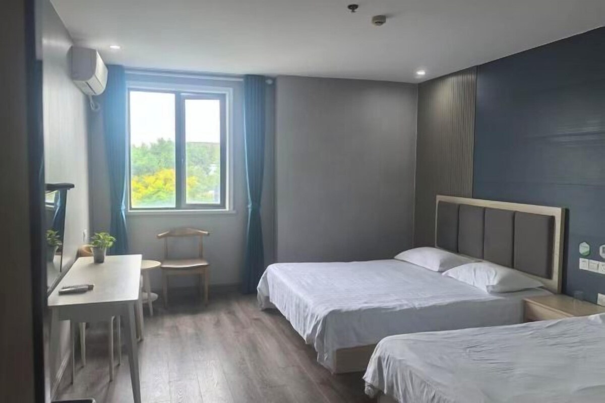 A bedroom with two beds, a desk, and a chair.