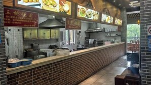 A restaurant interior with a brick counter, tiled backsplash, and menu boards displaying food images. - 99inn Selected Preferred Hotel (Shanghai Fengjing Ancient Town) (Shanghai)