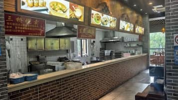 Ein Restaurantinneres mit einer Ziegel-Theke, Speisekarten und Blick ins Freie.