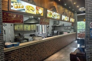 A restaurant interior with a brick counter, menu boards, and a view of the outdoors.