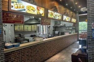 A restaurant interior with a brick counter, menu boards, and a view of the outdoors.