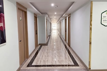 A long, narrow hotel corridor with doors on both sides, a tiled floor, and a sign on the right wall.. 99inn Selected Preferred Hotel (Shanghai Fengjing Ancient Town)