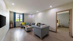 A modern living room with a grey sofa, a coffee table, and a TV mounted on the wall. - 99inn Selected Preferred Hotel (Shanghai Fengjing Ancient Town) (Shanghai)