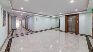 A spacious corridor with a polished floor, a wall-mounted sign, and an elevator. - 99inn Selected Preferred Hotel (Shanghai Fengjing Ancient Town) (Shanghai)