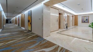 A hotel corridor with a marble floor, a central elevator, and framed artwork on the walls. - Tianzhu Mountain Wangfu International Hotel (Qianshan)