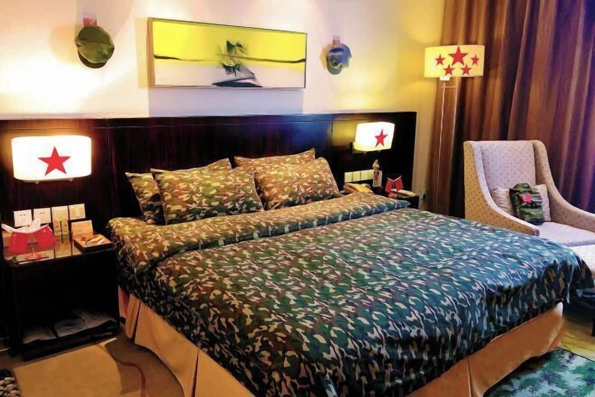 A hotel room with a large bed, two nightstands, a chair, and a wall-mounted lamp.