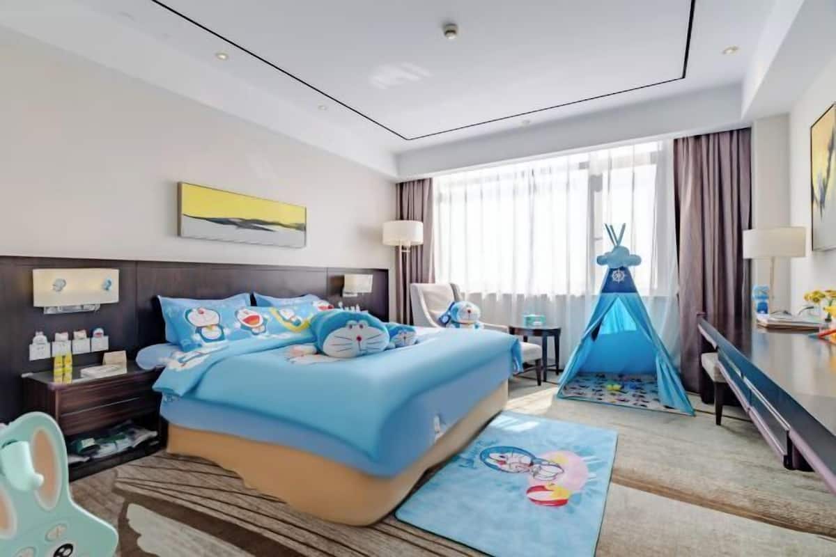 A hotel room with a bed, bedside table, lamp, and a blue tent-like structure.