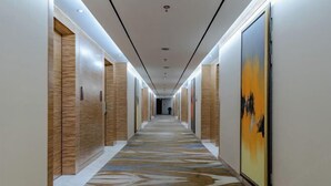 A long, narrow hallway with wooden doors on one side and a large painting on the other. - Tianzhu Mountain Wangfu International Hotel (Qianshan)