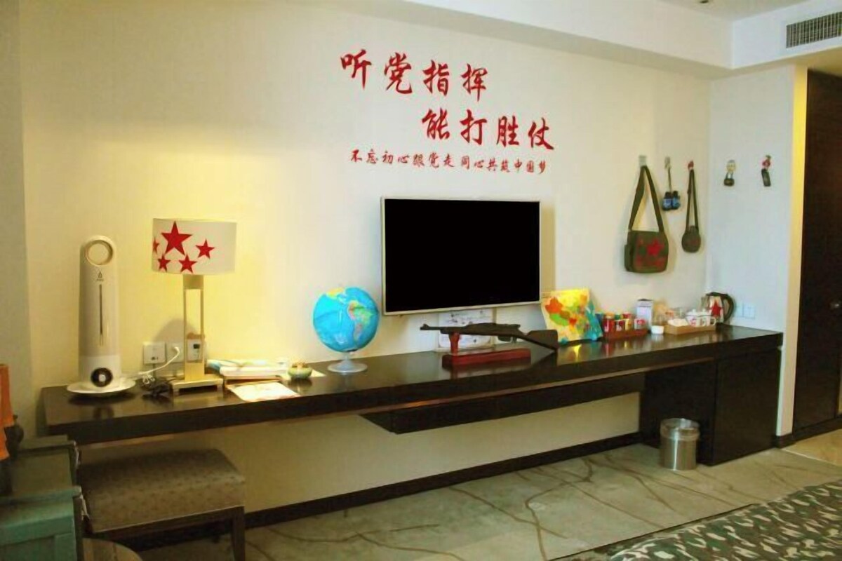 A reception area with a flat-screen TV, a globe, a desk with various items, and a wall with Chinese characters.