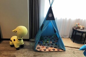 Una carpa azul con un emblema de estrella, un peluche y una pequeña mesa con un florero y una caja.