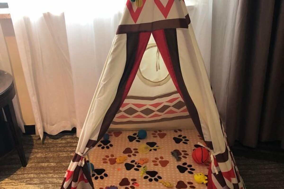 A tent-like play area with a patterned floor, curtains, and a small table.