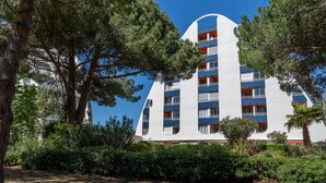 A modern building with a unique curved facade, surrounded by lush greenery and trees. - Les Marquises by Interhome (La Grande Motte)