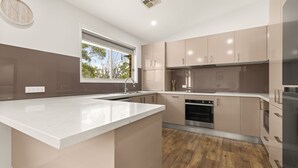 A modern kitchen with a large island, built-in oven, and a window providing natural light.