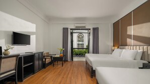 Quarto de hotel com uma cama, uma mesa, uma cadeira, uma televisão e vista para o exterior.