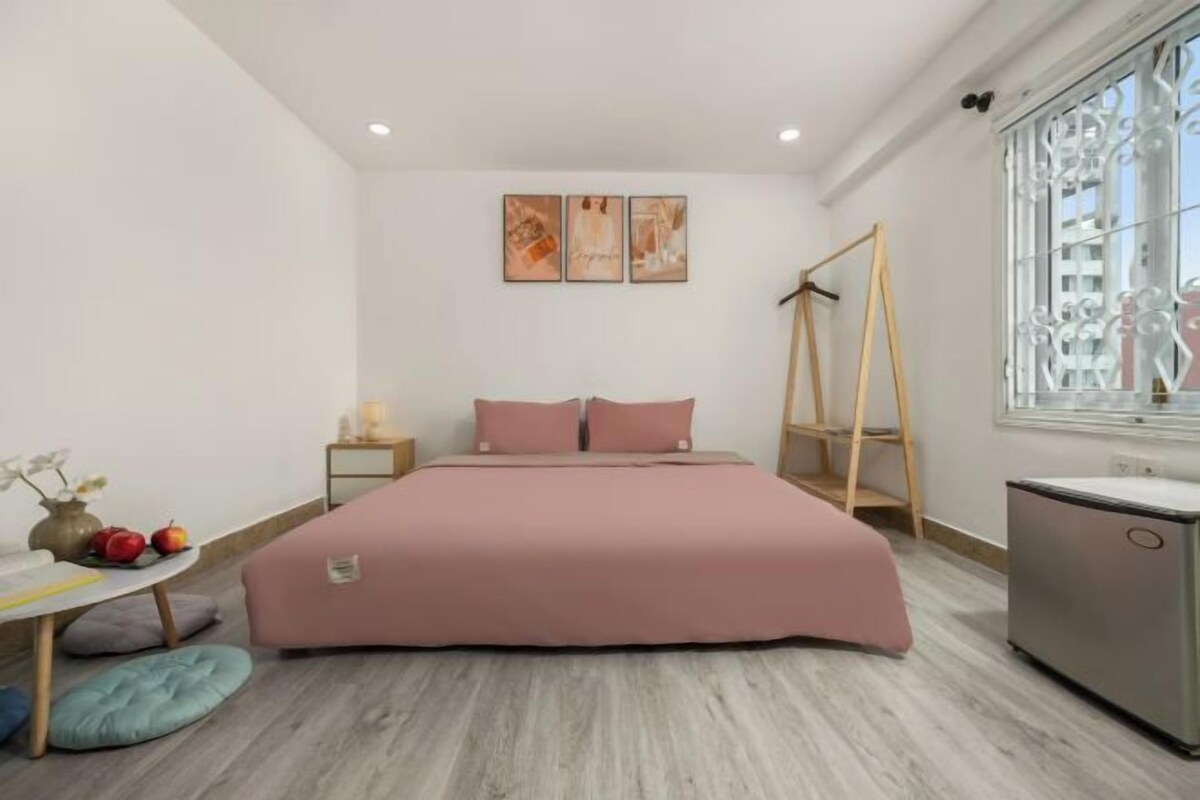 A bedroom with a bed, bedside tables, a desk, and a window.