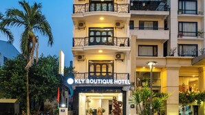 Um hotel com vários andares, varandas, uma entrada bem iluminada e uma placa com a inscrição 'KLY BOUTIQUE HOTEL'.