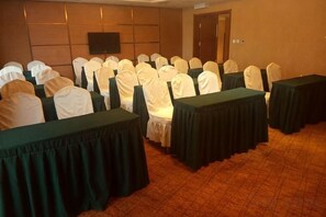 A conference room with rows of tables and chairs, a television screen, and a door in the background. - Xiying Holiday Hotel (Anshan)