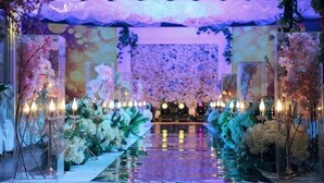 Un espacio interior con escenario, decoraciones florales y suelo reflectante.
