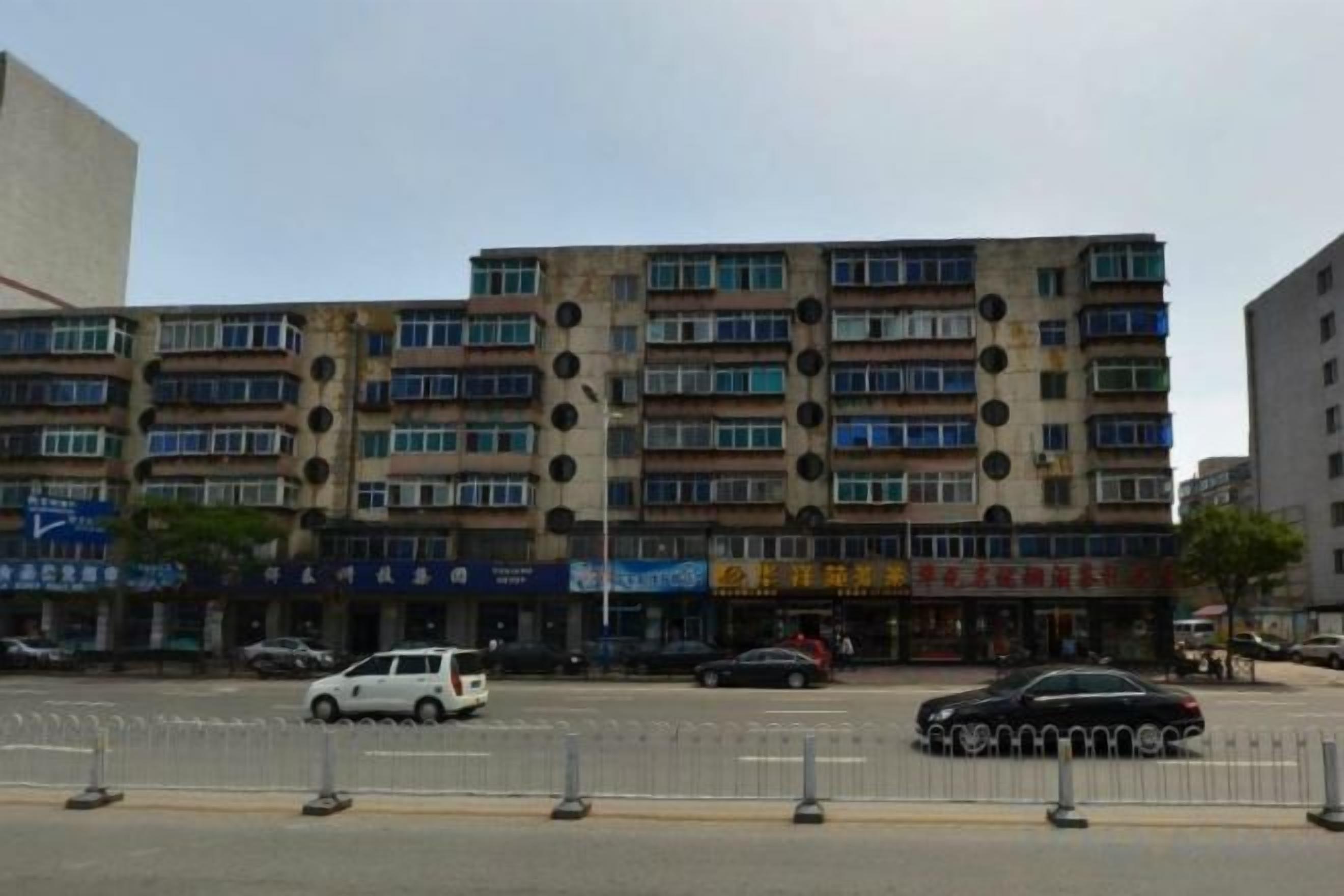 A multi-story building with a row of shops on the ground floor.