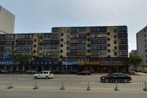 A multi-story building with a row of shops on the ground floor. - Xiying Holiday Hotel (Anshan)