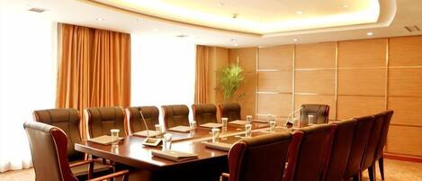 A conference room with a long table, multiple chairs, and a plant.