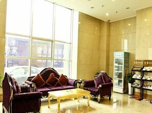 A lobby with a sofa set, a coffee table, and a shoe display. - Xiying Holiday Hotel (Anshan)