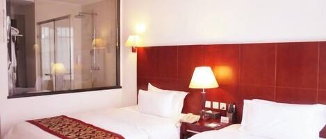 A hotel room with two beds, a large mirror, and a nightstand with a lamp.