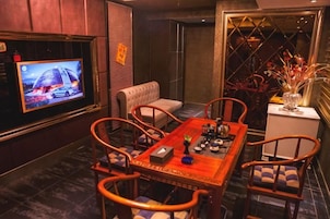 Un comedor con televisor, una mesa, sillas y un jarrón decorativo.