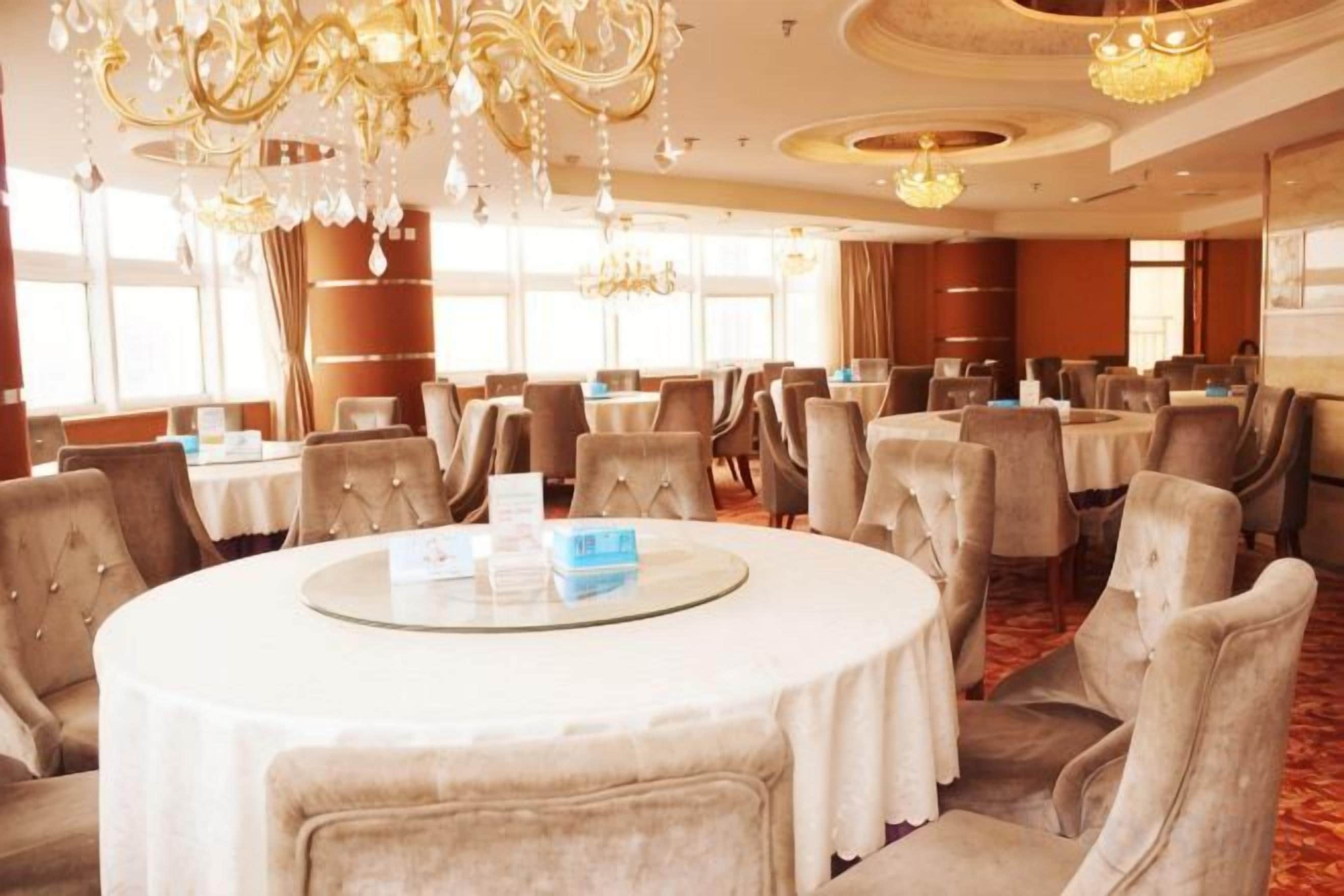 Un salón de conferencias de hotel con mesas redondas, sillas y candelabros.