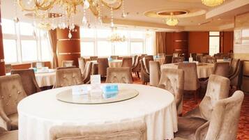 Un salón de conferencias de hotel con mesas redondas, sillas y candelabros.