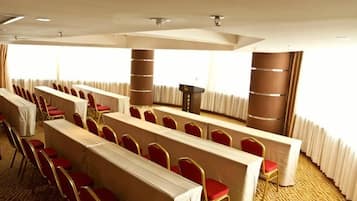 A conference room with rows of chairs, a podium, and a carpeted floor.