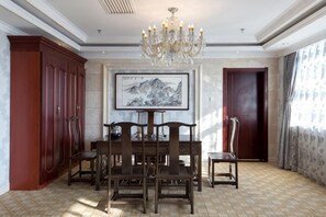 Un comedor con mesa y sillas de madera, una araña, una obra de arte enmarcada en la pared y un gran aparador de madera.